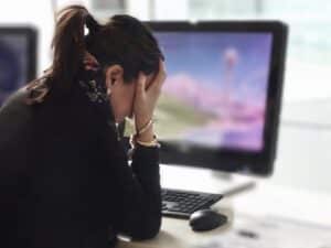 stressed out woman with head in hands at computer